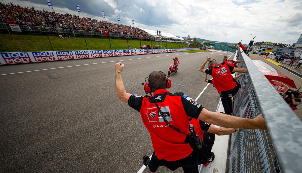 El equipo Ducati recibe, colgado del muro de Sachsenting, al piloto catalán como vencedor del GP.