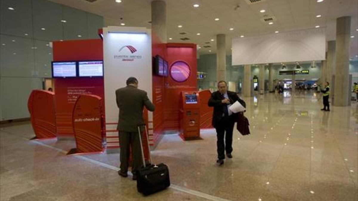 Dos viajerios se cruzan en la zona del puente aéreo de Barcelona.