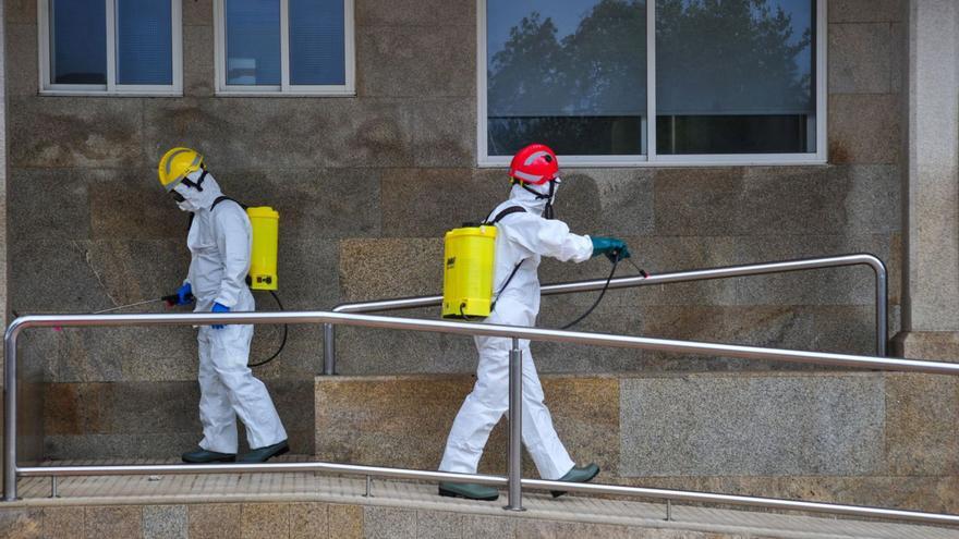 Dos bomberos desinfectan el centro de salud de Ribadumia al inicio de la pandemia. |  // IÑAKI ABELLA