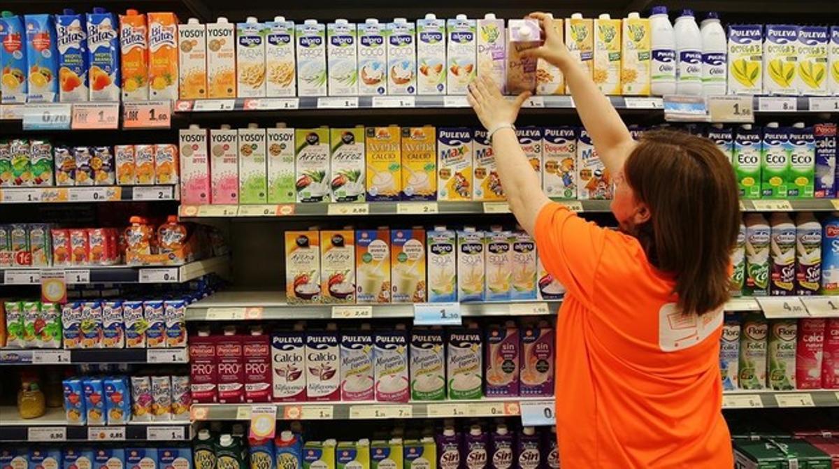 Una trabajadora ordena los productos en la estantería de un supermercado de Barcelona.  