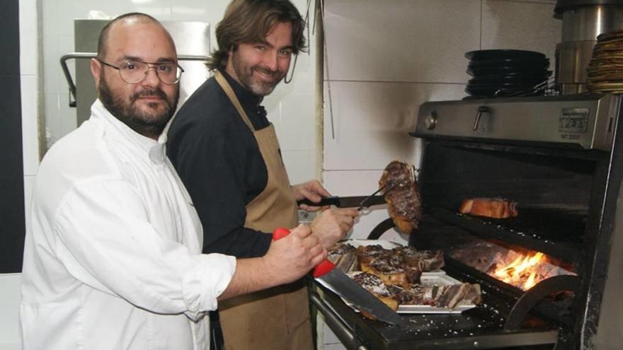 Mariano García, junto a Iñaki Gorrotxategi, ante las brasas del Asador La Pilar, en las Jornadas de la Carne Roja.