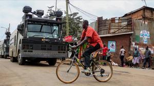 Un ciclista pasa por delante de un vehículo antidisturbios en las chabolas de Kibera, en Nairobi, el 7 de agosto.