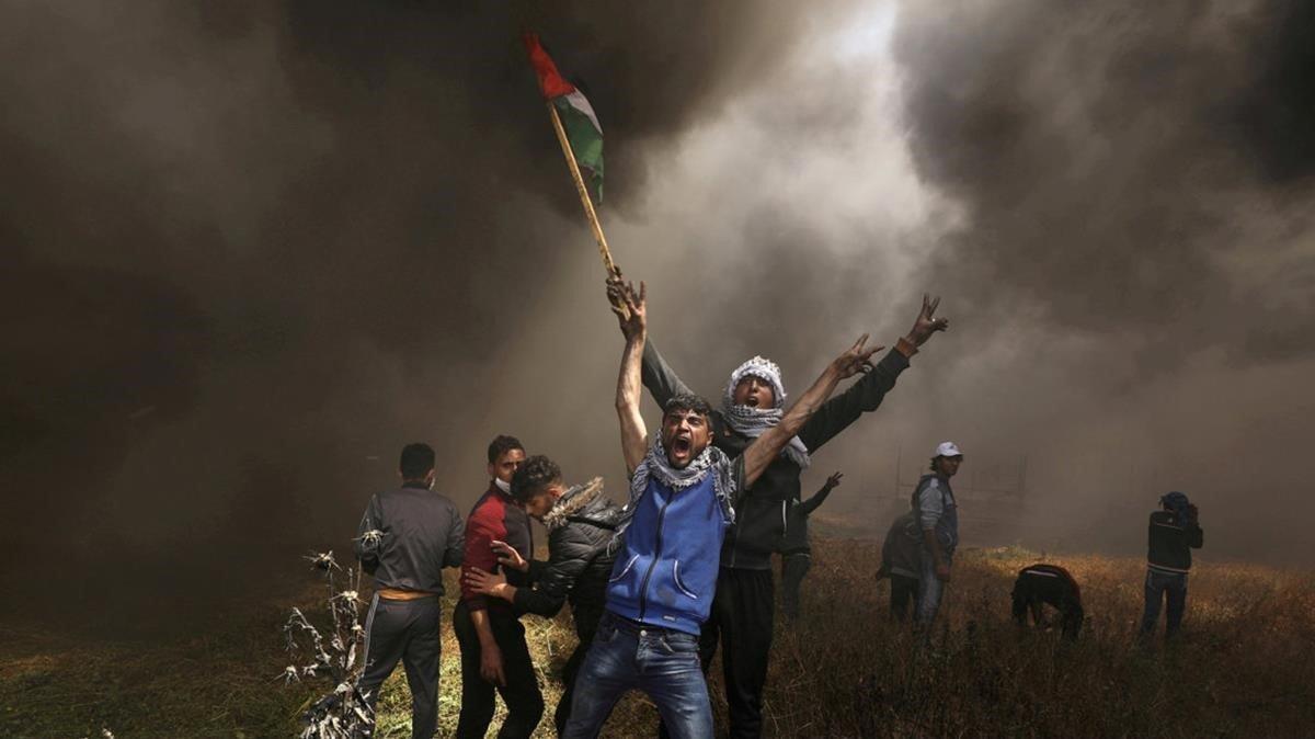 Jóvenes palestinos rodeados de nubes de humo en una de las protestas semanales palestinas a lo largo de la frontera entre Gaza e Israel y que fué noticia durante meses.