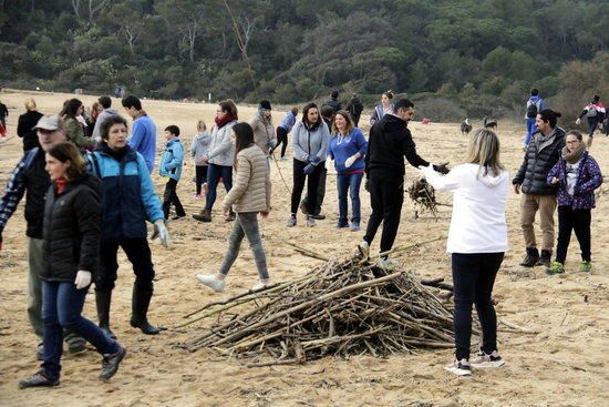 Un centenar de voluntaris recullen deixalles i apilen canyes a les platges de Palamós després del temporal