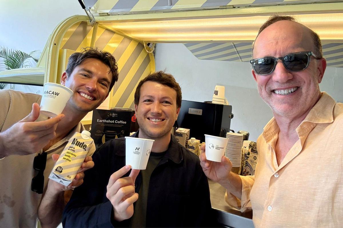 Parte del equipo de Nortpla con un vaso de café compostable con su logo.