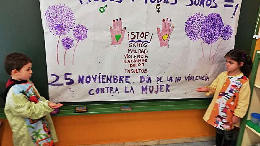 Dos alumnos de la escuela infantil Miguel Hernández, con el  mural del centro. 