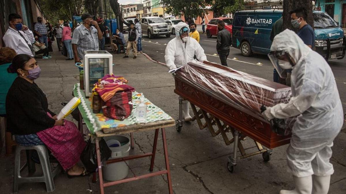 Dos empleados funerarios trasladan el féretro de una víctima de coronavirus en Ciudad de Guatemala