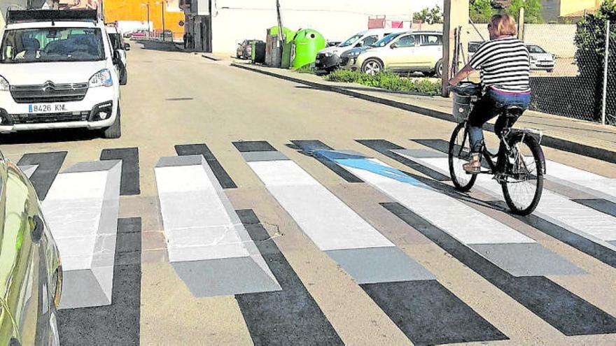 Una mujer circula en bicicleta sobre el paso de peatones de la calle Almàssera.