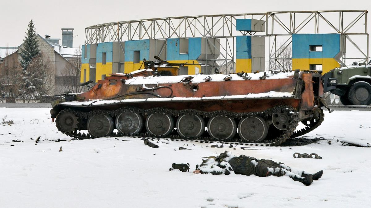 The body of a Russian serviceman lies near destroyed Russian military vehicles on the roadside on the outskirts of Kharkiv on February 26, 2022, following the Russian invasion of Ukraine. - Ukrainian forces repulsed a Russian attack on Kyiv but &quot;sabotage groups&quot; infiltrated the capital, officials said on February 26, as Ukraine reported 198 civilian deaths, including children, following Russia's invasion. A defiant Ukrainian President Volodymyr Zelensky vowed his pro-Western country would never give in to the Kremlin even as Russia said it had fired cruise missiles at military targets. (Photo by Sergey BOBOK / AFP)