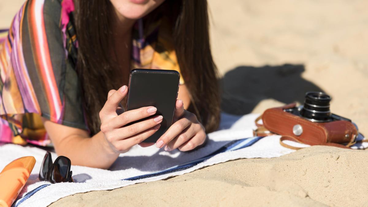 Una mujer usa el móvil en la playa