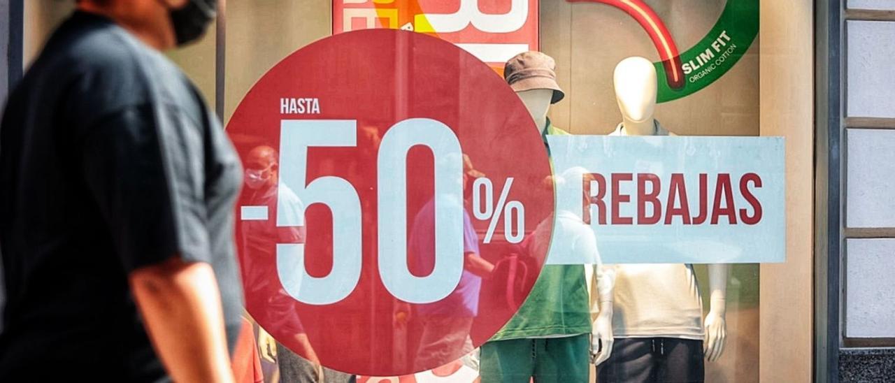 Varios peatones pasan por delante de un escaparate de la capital tinerfeña en la que se anuncia la temporada de rebajas.  | | MARÍA PISACA