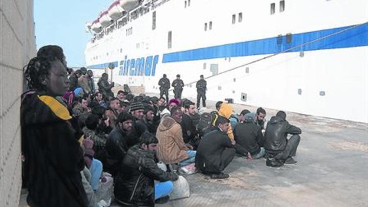 Grupos de inmigrantes esperan a ser trasladados desde Lampedusa a Sicilia, este jueves.