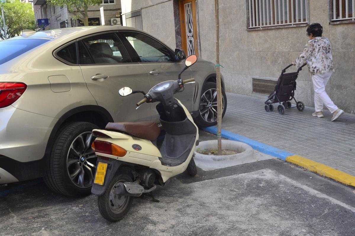 Una moto aparcada junto a un coche en Marqués de Asprillas, en Elche