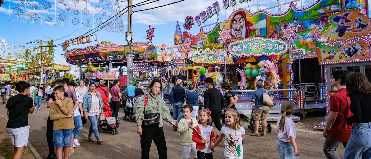 Padres y niños pasean por la calle del recinto entre las atracciones.