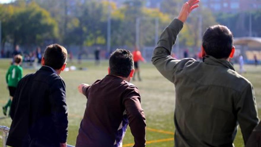 Tres padres gesticulan durante un partido de fútbol base, ayer en València.