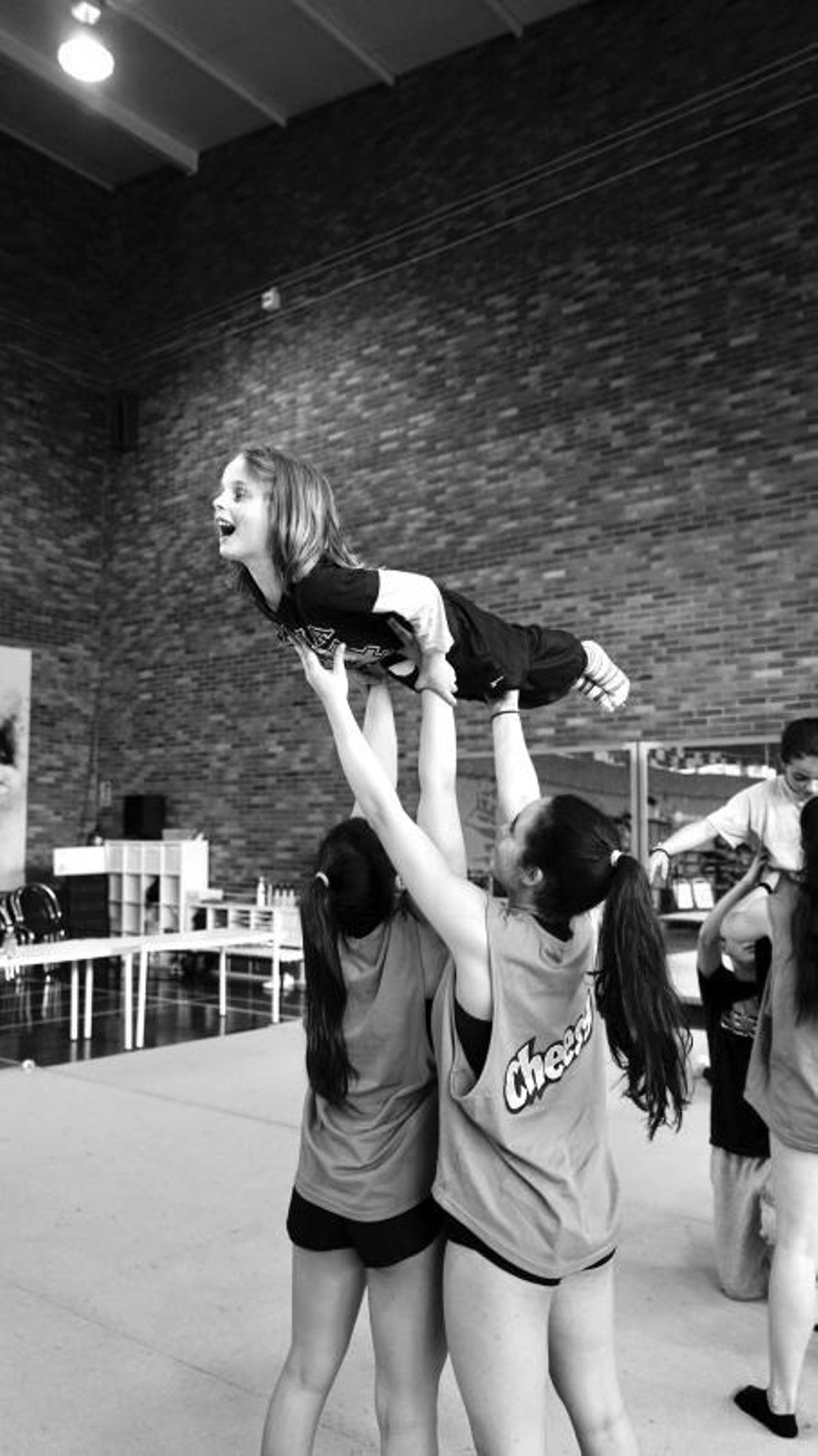 Una niña, sostenida pordos gimnastas del Flic Flac.