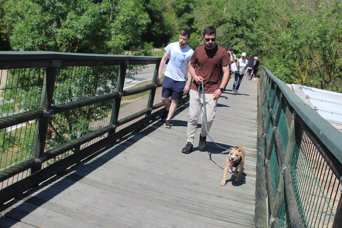 Gent passejant sobre el pont de fusta de la Muga