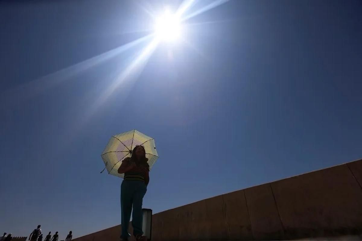 Una mujer se protege del sol con una sombrilla mientras camina por el centro de la Cordoba. EFE / Salas