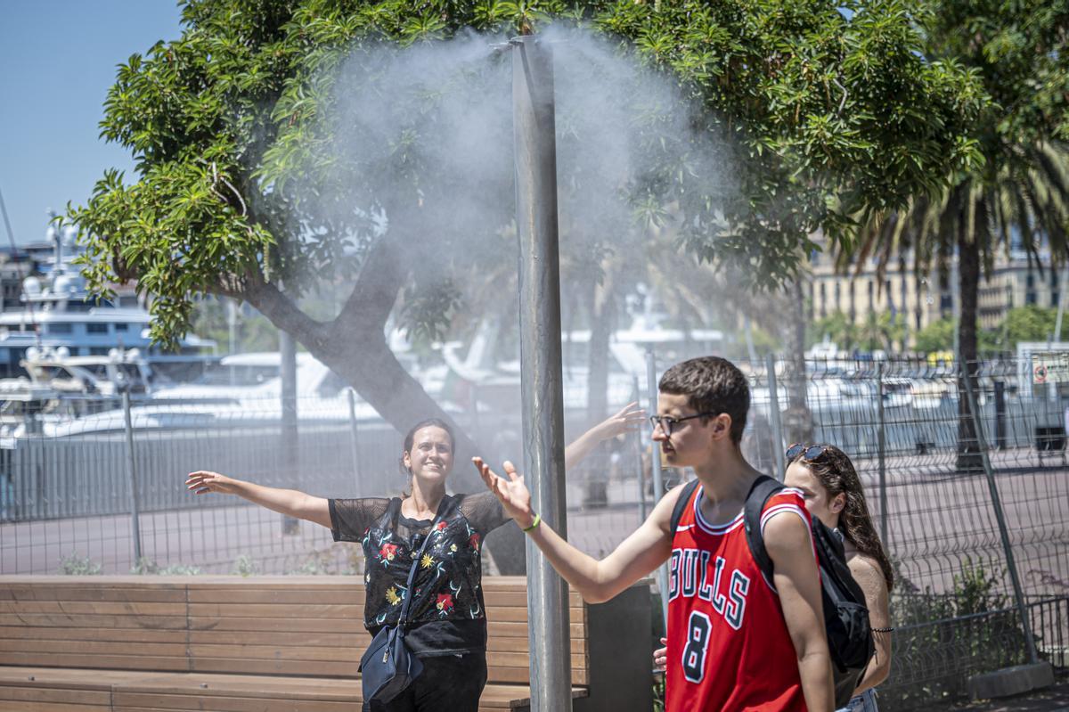 Paseantes disfrutan de un poco de vapor de agua refrescante en un refugio climático instalado cerca de la Barceloneta, en el paseo de Joan de Borbó.
