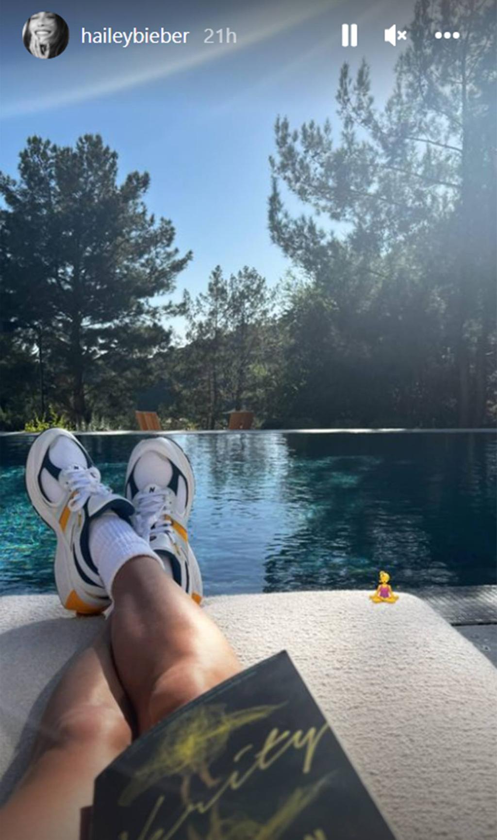 Hailey Bieber leyendo un libro en la piscina