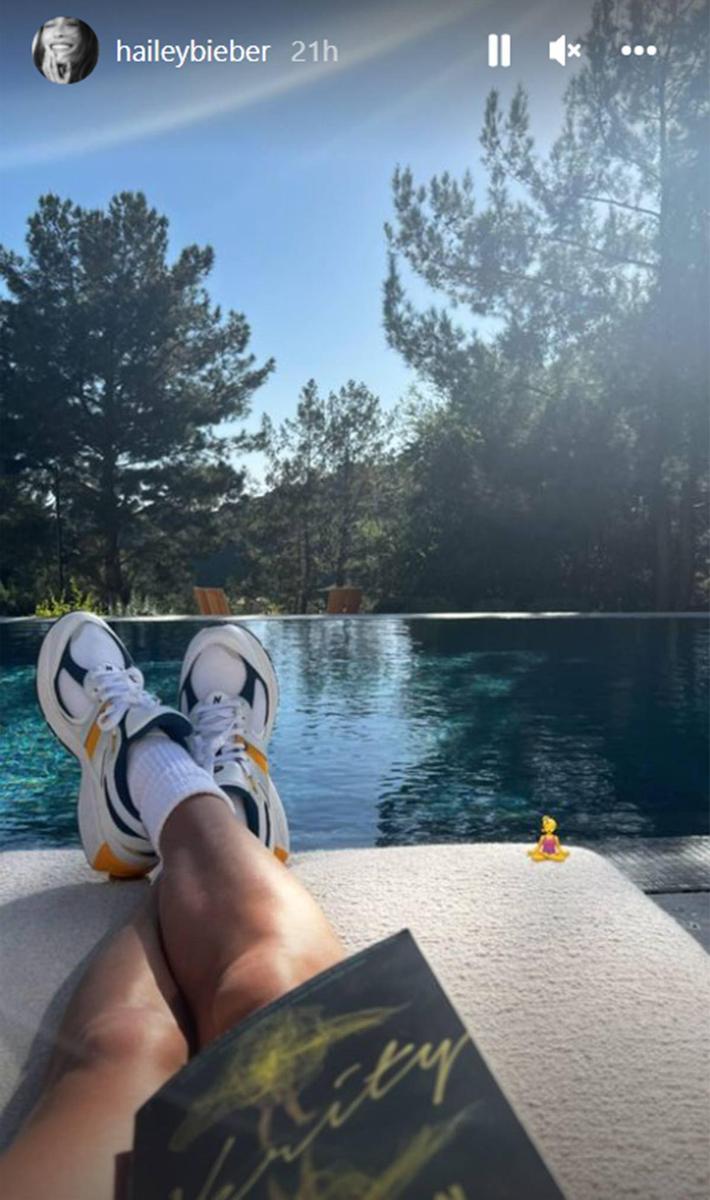 Hailey Bieber leyendo un libro en la piscina