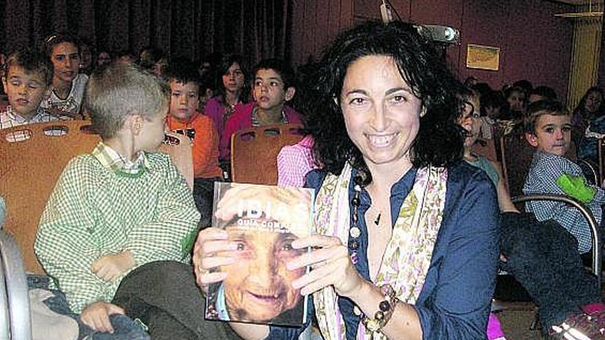 María del Roxo, sentada junto a los alumnos del Colegio Aurelio Menéndez de Ibias, muestra un ejemplar de su libro.