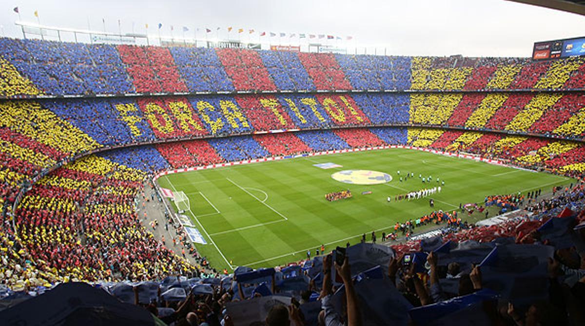 Els aficionats canten l’himne del Barça mentre formen un mosaic amb el lema ’Força, Tito!’ a les grades del Camp Nou, abans del clàssic.