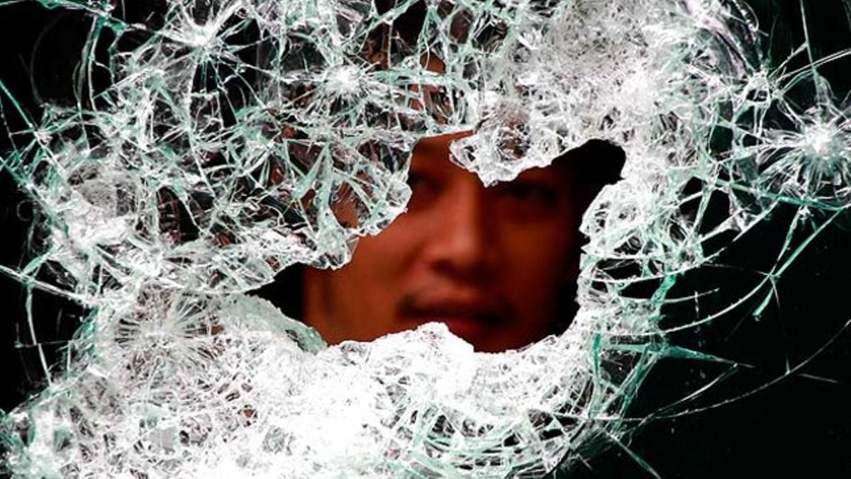 Un empleat del centre comercial més popular de Bangkok treu el cap per una finestra trencada.