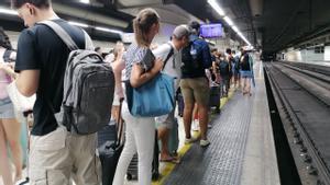 Pasajeros pendientes de pantalla y vías en Sants Estació en una mañana de demoras en la R2 de Rodalies