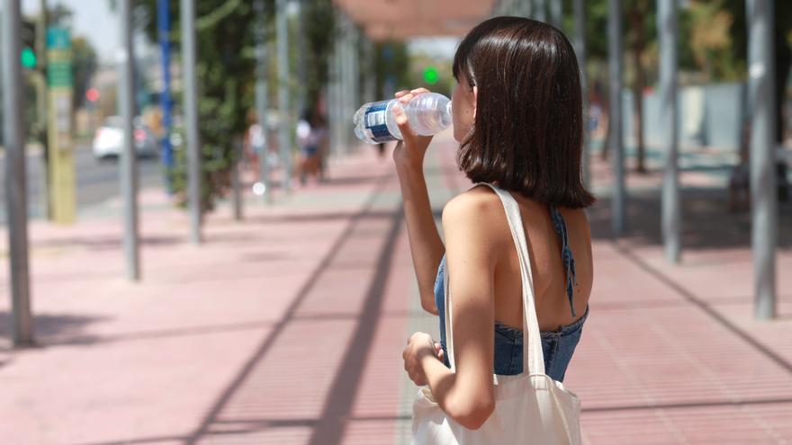 Una joven bebe agua para refrescarse ante las altas temperaturas en Sevilla, en imagen de archivo.