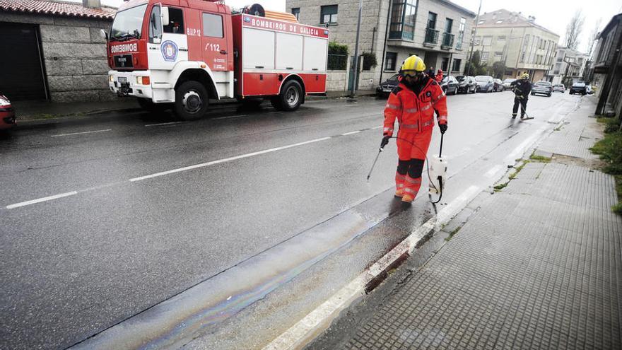 Un bombero limpia la mancha en la calle Os Olmos. // Iñaki Abella