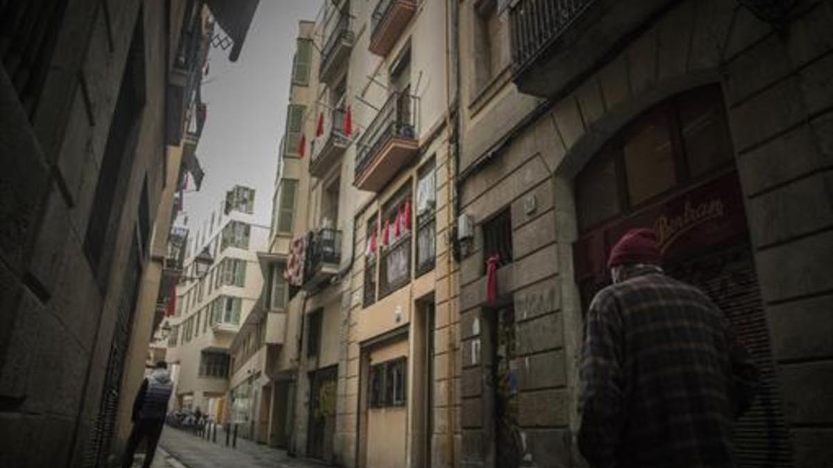 Pañuelos rojos cuelgan en las fachadas de los edificios de la calle de En Roig, en el Raval, para protestar por la venta de droga en la zona.