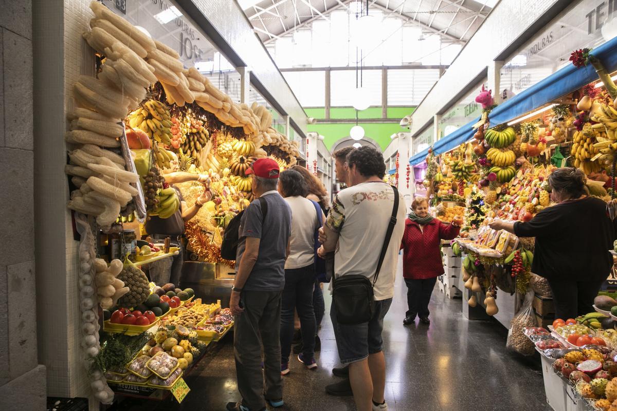 Clientes del mercado de Vegueta observan algunas frutas y verduras.