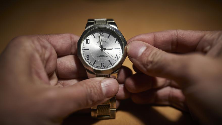 Un hombre cambia las manecillas de un reloj a las 3 horas, en Madrid (España)