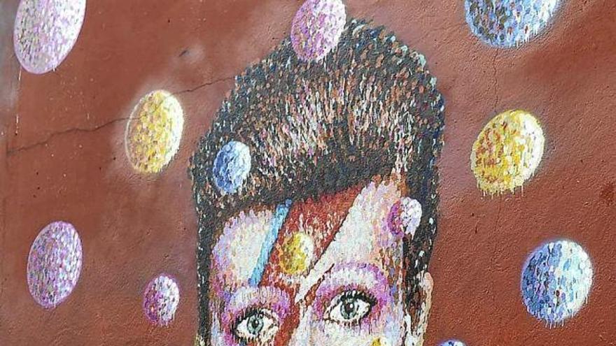 Una dona diposita flors davant un mural de Bowie, a Brixton