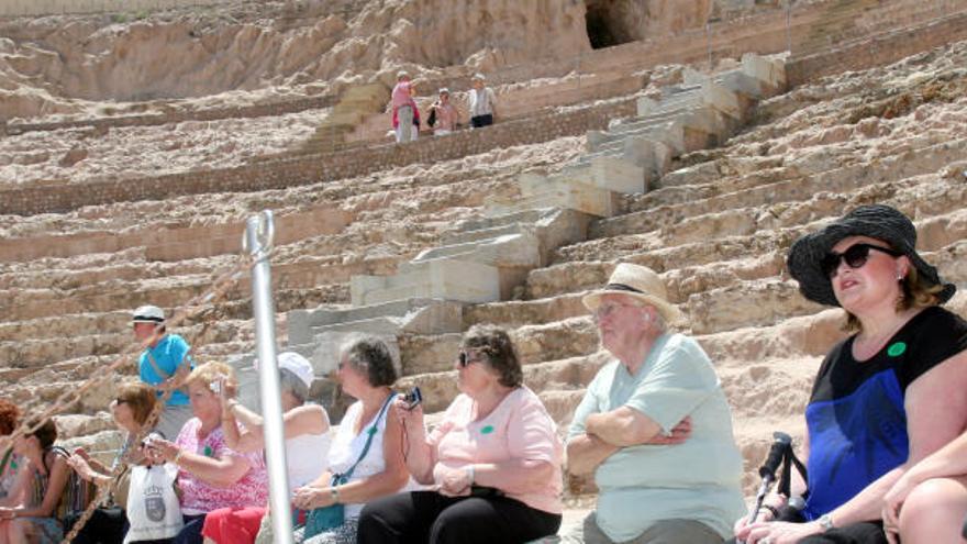 Un grupo de turistas observan el Teatro Romano desde una de sus graderías.