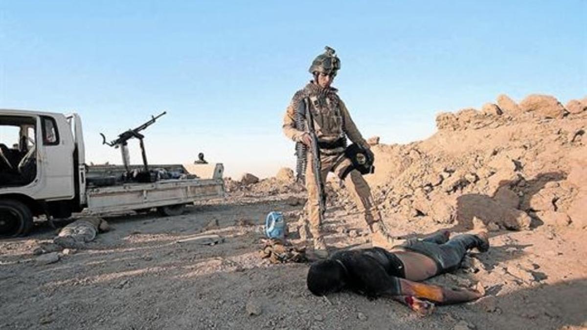 Un soldado iraquí, junto a un cuerpo sin vida en Babil, al sur de Irak.