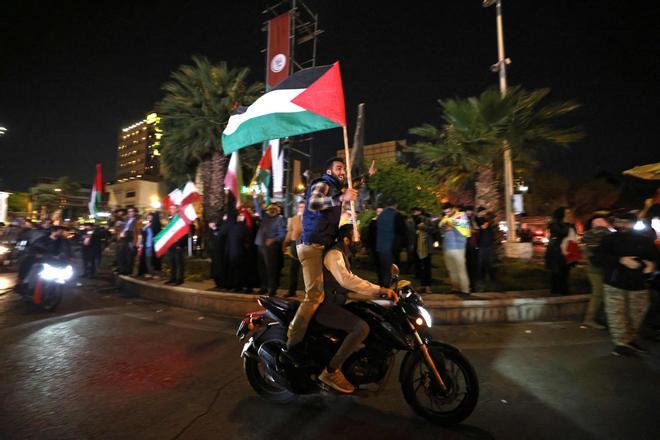 Manifestantes iranís ondean banderas de Palestina e Irán tras los ataques a Israel, la madrugada del domingo.