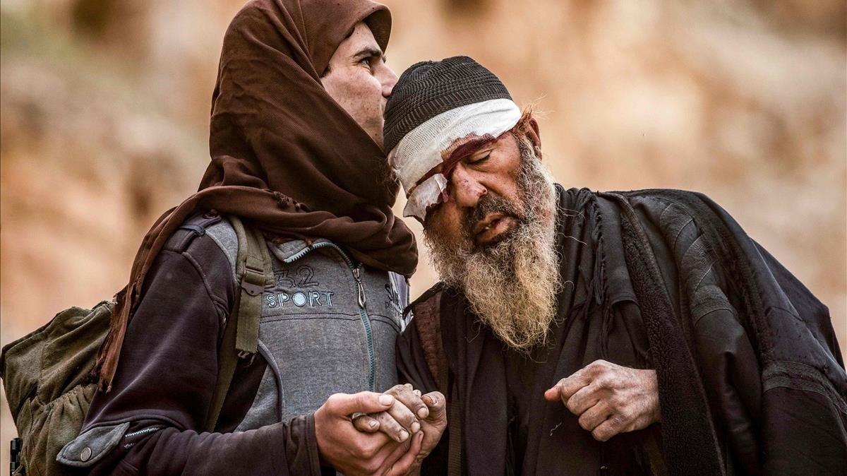 Un joven y un anciano malherido, presuntos militantes del Estado Islámico, salen de la aldea de Baghouz, en la provincia oriental siria de Deir Ezzor.