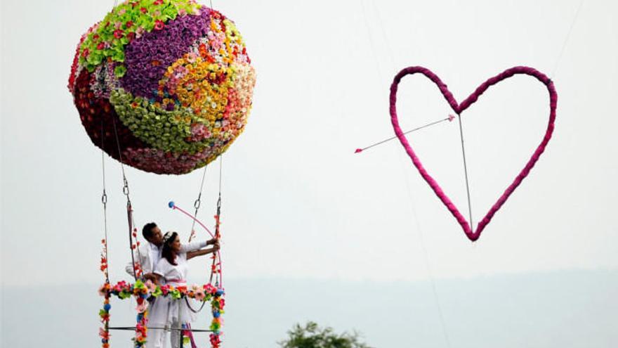 Una pareja lanza una flecha del amor desde un globo decorado con motivos florales. |
