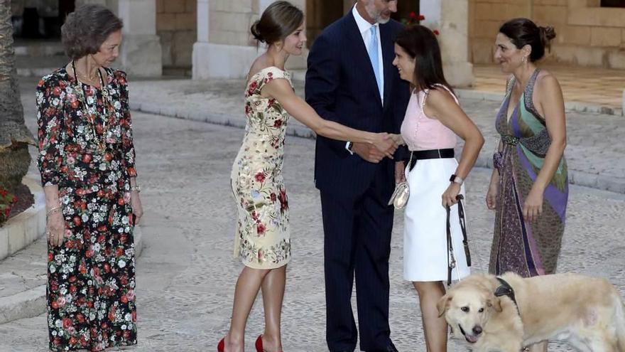 Los Reyes junto a doña Sofía saludan a una invitada invidente, acompañada por su perro guía.