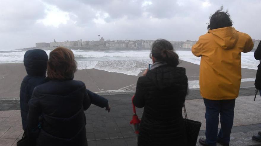 Varias personas observan el oleaje en A Coruña durante una alerta en la costa.