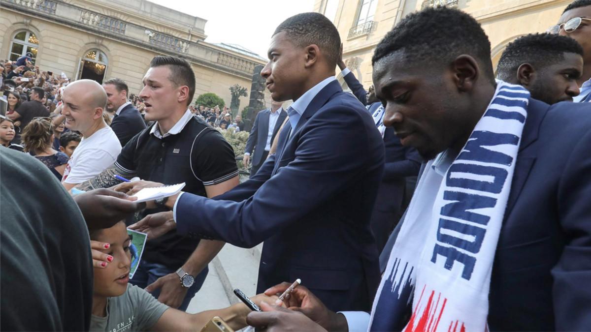 Dembélé (derecha) firma un autógrafo durante las celebraciones en París por la conquista del Mundial de Rusia