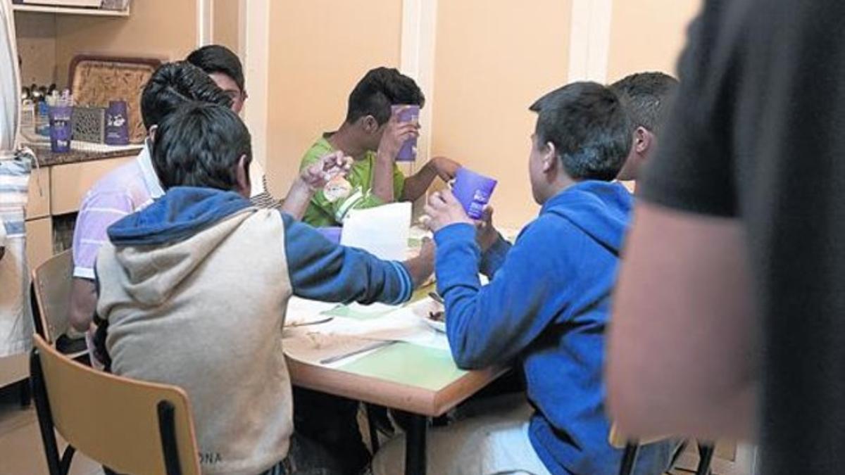 Un grupo de adolescentes, alumnos de instituto, toma el almuerzo en un centro abierto del barrio del Raval de Barcelona.