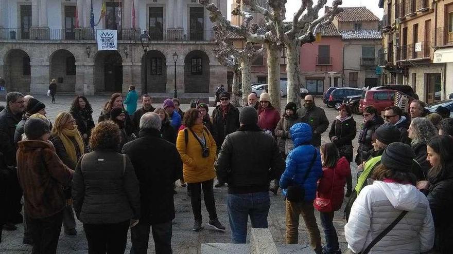 Turistas escuchan las explicaciones de una guía sobre la ciudad y su historia en un recorrido guiado.