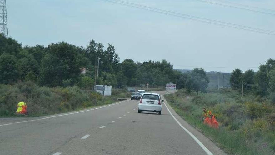 Dos operarios limpian cunetas en la carretera del Lago.