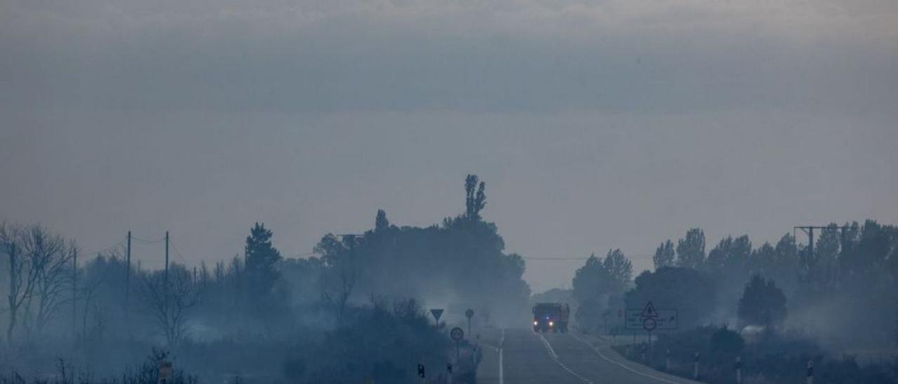 Un camión de bomberos en la vacía N-631, en medio de campos humeantes.| Emilio Fraile