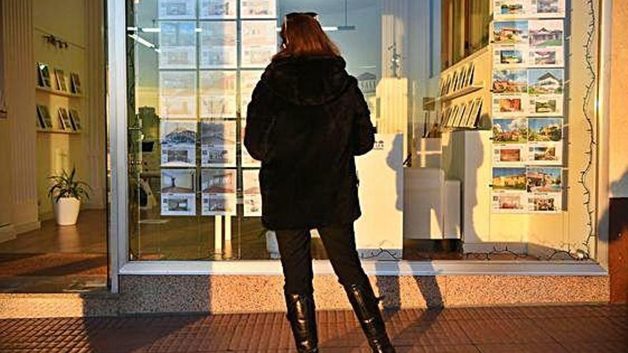 Una mujer observa un escaparate de una vivienda.