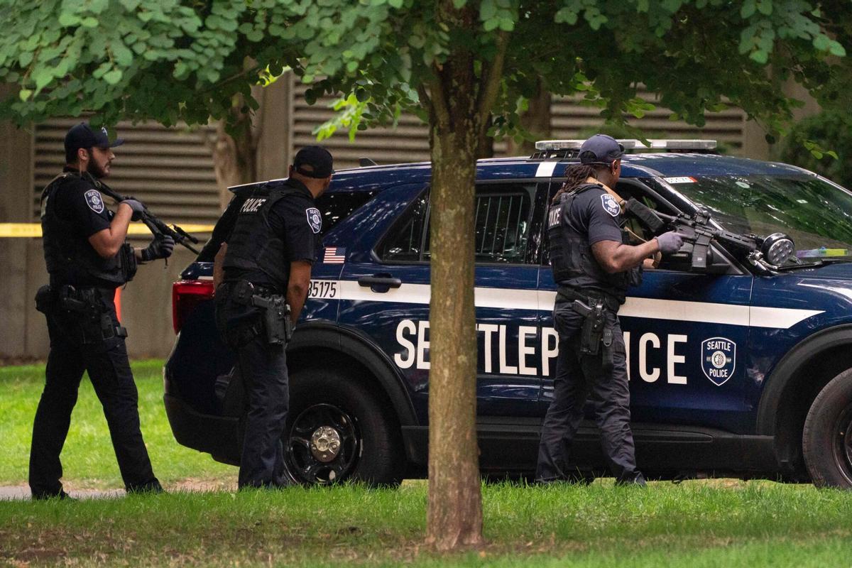 Un agente de policía apunta con su arma tras un vehículo policial después del tiroteo registrado durante el festival gastronómico Bite of Seattle Un agente de policía apunta con su arma tras un vehículo policial después del tiroteo registrado durante el festival gastronómico Bite of Seattle
