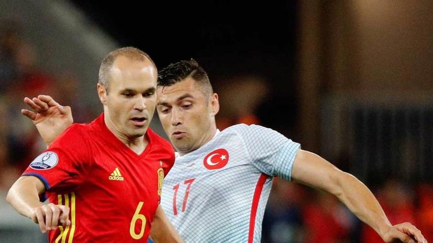 Andrés Iniesta se lleva el balón ante la presión del turco Burak Yilmaz.